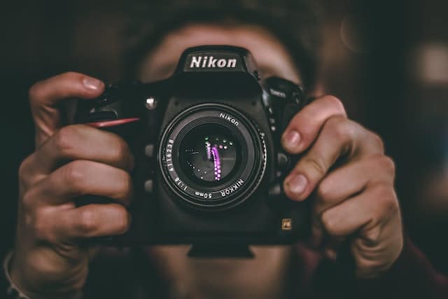 Eine Person hält eine Spiegelreflexkamera von Nikon in beiden Händen