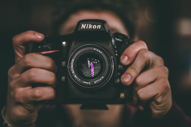 Eine Person hält eine Spiegelreflexkamera von Nikon in beiden Händen 